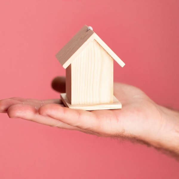 Una pequeña casa de madera sobre la mano de una persona